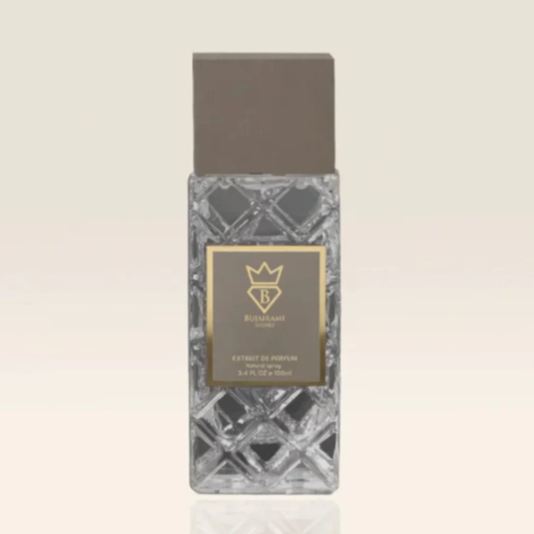 Bujairami World Power Oud Cacao Leather 100ml Extrait — Clear faceted glass bottle with a grey cap and a gold label featuring a crown and 'B' logo, text reads 'EXTRACT DE PARFUM NATURAL SPRAY 3.4 FL. OZ. 100ml'
