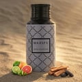 Majesty by Maison Asrar 100ml EDP Unisex — Botol bertutup hitam dan badan bercorak putih, diletakkan di atas pasir bersama buah limau gedang, limau nipis, dan ketulan kayu.