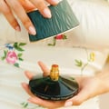Maison Asrar Never Forget Me 90ml EDP Women — Tangan wanita memegang penutup botol minyak wangi Maison Asrar Never Forget Me berwarna hijau gelap bertekstur dan botolnya, menampakkan muncung semburan emas.