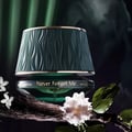 Maison Asrar Never Forget Me by Maison Asrar 90ml EDP Women — Penutup bertekstur hijau berombak dengan trim emas, pada botol kaca jernih berisi cecair hijau, diletakkan di atas dahan kayu gelap dengan bunga melur putih.