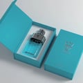 Bujairami No Limit by Bujairami 100ml EDP Unisex — A blue perfume bottle with a honeycomb pattern and a silver cap sits inside an open turquoise box with a honeycomb pattern on the lid. | Bujairami No Limit by Bujairami 100ml EDP Unisex — Botol minyak wangi biru dengan corak sarang lebah dan penutup perak terletak di