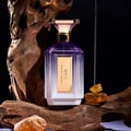 Velixir Nyx Velixir Parfums 100ml for Unisex — A faceted purple and white glass perfume bottle with a gold cap and label, placed among rough wood and amber-like stones on a dark background. | Velixir Nyx Velixir Parfums 100ml for Unisex — Botol kaca ungu dan putih berfaset dengan penutup dan label emas, diletakkan di