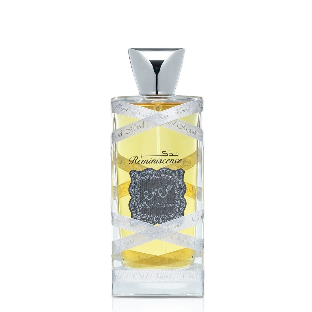 Lattafa Oud Mood Reminiscence Lattafa 100ml — A clear glass perfume bottle with yellow liquid, wrapped in a silver ribbon printed with 'Oud Mood'. The bottle has a silver cap and a dark grey label with Arabic script and 'Reminiscence' text. | Lattafa Oud Mood Reminiscence Lattafa 100ml — Botol kaca jernih berisi