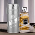 Lattafa Oud Mood Reminiscence — Silver cylindrical box and a clear glass perfume bottle with gold liquid, both featuring ornate silver ribbon details and Arabic script. | Lattafa Oud Mood Reminiscence — Kotak silinder perak dan botol minyak wangi kaca jernih dengan cecair emas, kedua-duanya menampilkan perincian reben