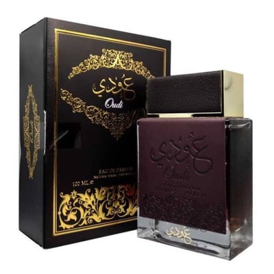 Ard Al Zaafaran Oudi Eau De Parfum 100ml — A brown perfume bottle with a textured cap and embossed Arabic calligraphy and 'Oudi' text, stands next to its matching dark brown box with gold ornate patterns and text. | Ard Al Zaafaran Oudi Eau De Parfum 100ml — Botol minyak wangi coklat dengan penutup bertekstur dan