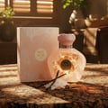 Afnan 9 AM – Pour Femme by Afnan Perfumes – 100 ml for Women — Hand holding perfume bottle next to pink box on vanity