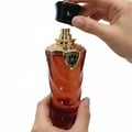 Afnan Supremacy In Oud — Amber glass perfume bottle with gold cap and emblem, next to a matching copper box with embossed