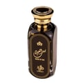 Afnan Supremacy Incense — A broken blue perfume bottle lies on a wet, reflective surface with colorful light reflections and