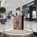 Al Wataniah Ain Emarat — Brown ribbed box with gold eagle emblem next to amber glass perfume bottle with gold accents
