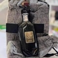 Ard Al Zaafaran Daar Al Haneen Women — Perfume bottle with gold lace, black rose accent, and yellow-orange powder explosion