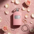 Ard Al Zaafaran Ajmal Ehsas Bloom — Pink roses, makeup brushes, blush compacts, lipstick, and perfume bottle arranged on a