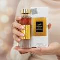 Ard Al Zaafaran Ghality — Broken perfume bottle with roses and smoke emerging, a woman watches in surprise.