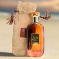 Ard Al Zaafaran Bint Hooran — Hand spraying perfume bottle next to its gold box and white flowers on satin