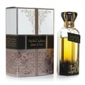 Ard Al Zaafaran I Am The King — A dark coffee cup sits on a saucer next to a perfume box and bottle on a wooden table.