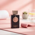 Ard Al Zaafaran Oud Fazza — Clear glass perfume bottle with gold cap and ornate gold circular patterns, next to its white