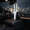 Ard Al Zaafaran Shams Al Emarat Khususi — Red perfume bottle with crystal cap inside a luxury car at night with city skyline.