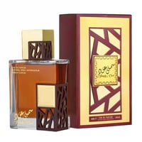 Lattafa Simply Oud by Lattafa 100ml EDP untuk Lelaki — Botol minyak wangi kaca perang dengan perincian kayu dan emas yang indah, bersebelahan dengan kotak corak merah marun dan emasnya.