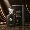 Maison Alhambra Perseus Exclusif — Black perfume bottle with a silver crest-like cap and a circular emblem featuring a deer, next to its black textured box with silver accents, set against a dark, draped background. | Maison Alhambra Perseus Exclusif — Botol minyak wangi hitam dengan penutup seperti puncak perak dan