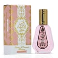 Ard Al Zaafaran Pink Blush Shams Al Emarat Khususi — Pink perfume bottle with gold cap next to its pink and gold patterned box, isolated on white.