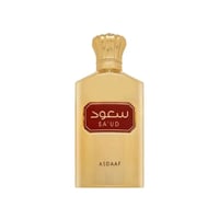 Asdaaf Sa'ud by Asdaaf 100ml EDP Unisex — Botol minyak wangi emas dengan penutup berbentuk mahkota dan label merah bertulis skrip Arab "SA'UD". Nama jenama "ASDAAF" kelihatan di bahagian bawah.