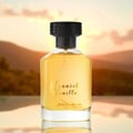 Al Rehab Spanish Vanilla Eau De Parfum 100ml — A clear glass perfume bottle with yellow liquid and a black cap, set against a blurred background of hills and a sunset sky. | Al Rehab Spanish Vanilla Eau De Parfum 100ml — Botol kaca jernih berisi cecair kuning dan bertutup hitam, berlatar belakang kabur bukit dan