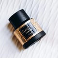 Lattafa Tamima by Lattafa 100 ml Eau de Parfum — Black perfume bottle with ornate gold detailing and a black cap, set against a textured white background. | Botol minyak wangi hitam dengan perincian emas berhias dan penutup hitam, diletakkan di atas latar belakang putih bertekstur.
