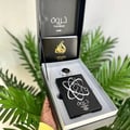 Lattafa Pride Tharwah Silver by Lattafa Pride 100ml EDP — Kotak hadiah hitam terbuka, memaparkan botol minyak wangi hitam dengan rekaan atom perak, penutup perak, dan buku kecil.