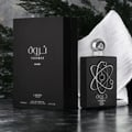 Lattafa Pride Tharwah Silver — Kotak dan botol minyak wangi hitam dengan rekaan atom perak, di atas permukaan gelap berkilat dengan kehijauan dan kain putih.
