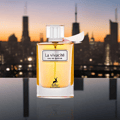 Maison Alhambra La Vivacite Eau de Parfum — A clear glass perfume bottle with golden liquid, featuring a white label with black text and a silhouette of a deer, set against a blurred city skyline at sunset.