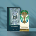 Maison Alhambra La Charmante by Maison Alhambra 100ml EDP — A perfume bottle with a peacock-inspired gold and green cap stands next to its matching dark teal box with art deco design.