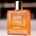 Rayhaan Adonis Icarus Rayhaan Perfume 100ml — A square, amber-colored glass perfume bottle with a gold cap, featuring embossed Arabic calligraphy and text "ADONIS ICARUS RAYHAAN" on the front. | Rayhaan Adonis Icarus Rayhaan Perfume 100ml — Botol kaca berbentuk segi empat berwarna ambar dengan penutup emas