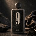 Afnan 9 PM Night Out Extrait de Parfum — A textured grey bottle with a black label featuring a large white '9' and 'pm' below it, set against a dark, dramatic background with rocks and draped fabric. | Afnan 9 PM Night Out Extrait de Parfum — Botol kelabu bertekstur dengan label hitam memaparkan '9' putih besar dan