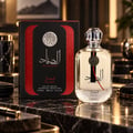 Ard Al Zaafaran Al Sayaad For Men Ard Al Zaafaran 100ml EDP — Black and red box with Arabic calligraphy and silver emblem next to a clear glass perfume bottle with silver cap, on a marble surface.