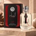 Ard Al Zaafaran Al Sayaad For Men EDP — Black and red box with Arabic calligraphy and silver emblem next to a clear glass perfume bottle with silver cap and matching emblem.