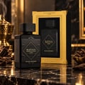 Lattafa Bade'e Al Oud Black Exposed Lattafa 100ml — Black perfume bottle and its gold-accented box displayed on a marble surface with oud wood chips and a golden incense burner in the background.