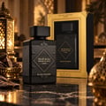 Lattafa Bade'e Al Oud Black Exposed Lattafa 100ml — Black perfume bottle with ornate gold detailing on a marble surface, next to its gold-trimmed display box and oud wood chips.