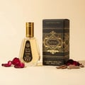 Ard Al Zaafaran Badee Al Oud Eau De Parfum 50ml — A clear glass perfume bottle with a gold cap sits next to its black and gold patterned box, surrounded by rose petals and oud wood chips on a cream background. | Ard Al Zaafaran Badee Al Oud Eau De Parfum 50ml — Botol minyak wangi kaca jernih bertutup emas terletak di