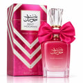 Ard Al Zaafaran Bint Hooran Rose Passion — Pink perfume bottle with a large satin bow, crystal cap, and matching box with gold accents on a reflective surface.