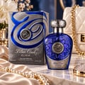 Lattafa Blue Oud Elixir — Blue glass perfume bottle with ornate silver cap, next to its silver and blue patterned box, on a marble surface with silk fabric and pearls.