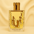 Maison Alhambra Sugar Me Creme Brulee — A square glass perfume bottle with golden liquid and a gold cap designed to look like dripping caramel. The bottle has a decorative caramel drip design on the front. Text reads 'SUGAR ME CREME BRULEE'.