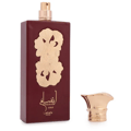 Lattafa Pride Ansaam Gold — A maroon perfume bottle with gold floral embellishments and gold cap detached, placed next to the bottle.