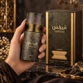 Lattafa Fearless by Lattafa 100ml EDP Men — Hand holding a textured dark grey and gold bottle of Lattafa Fearless perfume, with the matching box in the background.