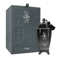 Zimaya Ghali Imperial Eau De Parfum 100ml by Zimaya — A dark grey textured box with a building facade pattern stands next to a dark, ornate perfume bottle with a tassel. | Zimaya Ghali Imperial Eau De Parfum 100ml by Zimaya — Kotak kelabu gelap bertekstur dengan corak fasad bangunan berdiri di sebelah botol minyak