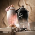 Zimaya Ghali Imperial Eau De Parfum 100ml by Zimaya — Two ornate perfume bottles, one pink and one black, with tassels and gold accents, displayed on a reflective surface with a textured background. | Dua botol minyak wangi berhias, satu berwarna merah jambu dan satu hitam, dengan juntai dan perincian emas, dipamerkan