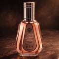 Ard Al Zaafaran Hareem Al Sultan EDP 50ml — A clear glass perfume bottle with rose gold accents and a rose gold liquid, set against a dark, textured background. | Ard Al Zaafaran Hareem Al Sultan EDP 50ml — Botol minyak wangi kaca jernih dengan aksen emas mawar dan cecair emas mawar, diletakkan di atas latar belakang
