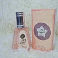 Ard Al Zaafaran Hareem Al Sultan EDP 50ml — A clear glass perfume bottle with a silver cap and a pink label sits next to its peach-colored box with a purple circular design. | Ard Al Zaafaran Hareem Al Sultan EDP 50ml — Botol minyak wangi kaca jernih dengan penutup perak dan label merah jambu terletak di sebelah kotak