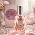 Ard Al Zaafaran Hareem Al Sultan EDP 50ml — A pink perfume bottle with a silver cap sits on a surface with draped pink fabric, pearls, and a matching pink and white patterned box in the background. | Ard Al Zaafaran Hareem Al Sultan EDP 50ml — Sebotol minyak wangi berwarna merah jambu dengan penutup perak diletakkan