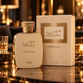 RASASI Hawas Addiction by Rasasi 100ml EDP — Botol minyak wangi tona emas dan kotak sepadan dengan panel emas bertekstur, diletakkan di atas permukaan gelap yang memantul dengan segelas cecair keemasan di latar belakang.