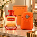 Kenz de Rasasi Hawas Apex — Botol minyak wangi oren dan sarung sepadan dengan logo timbul, di atas permukaan marmar dengan susunan bunga di latar belakang