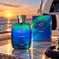RASASI Hawas Atlantis by Rasasi 100ml EDP — Botol minyak wangi kaca gradien biru dan hijau dengan penutup perak bertekstur, diletakkan di atas permukaan marmar bersebelahan kotak padanannya, dengan latar belakang kapal layar dan matahari terbenam di lautan.